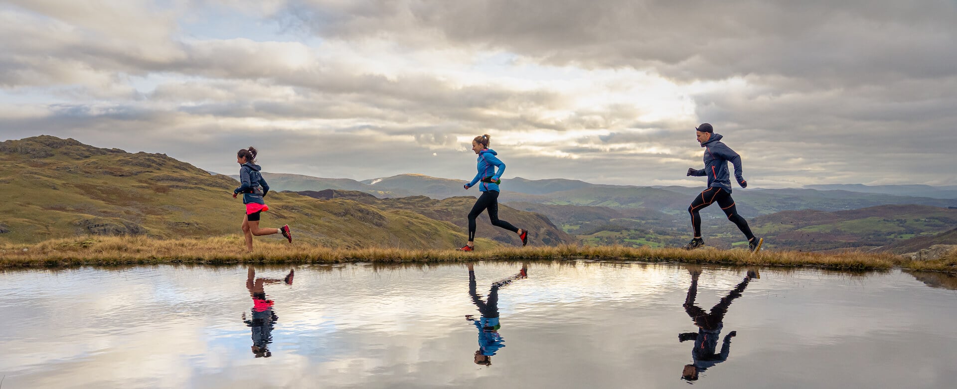 OMM runners passing a mountain tarn.