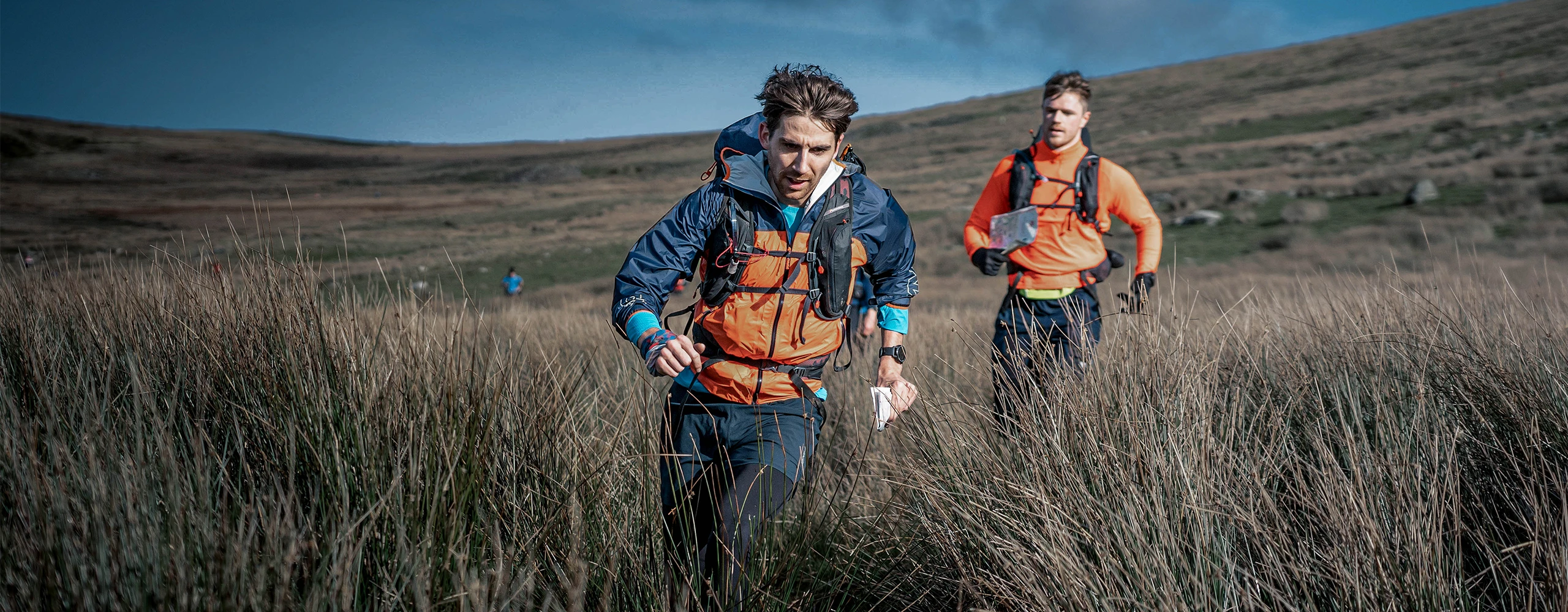 Two OMM competitors running through open mountain terrain