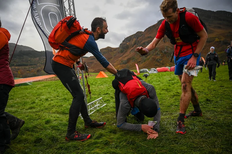 An OMM competitor crossing a ridge beneath rocky mountain peaks