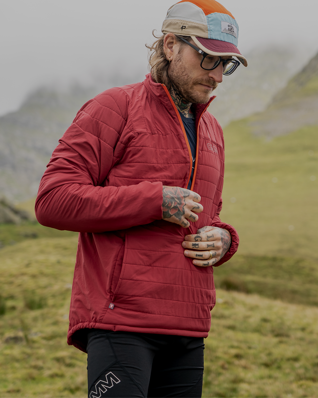 Runner wearing a red insulated OMM jacket in the hills